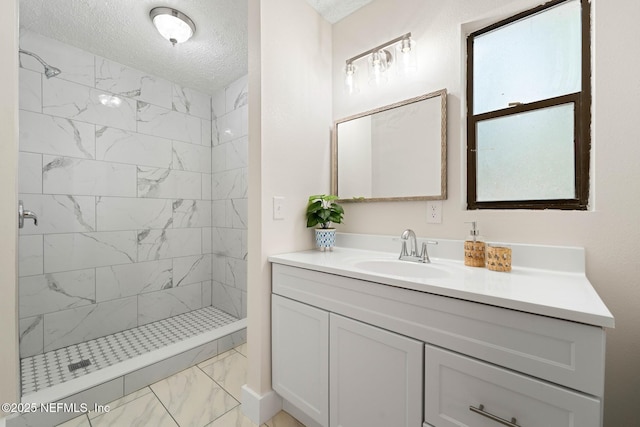 full bathroom featuring vanity, a textured ceiling, marble finish floor, and a shower stall
