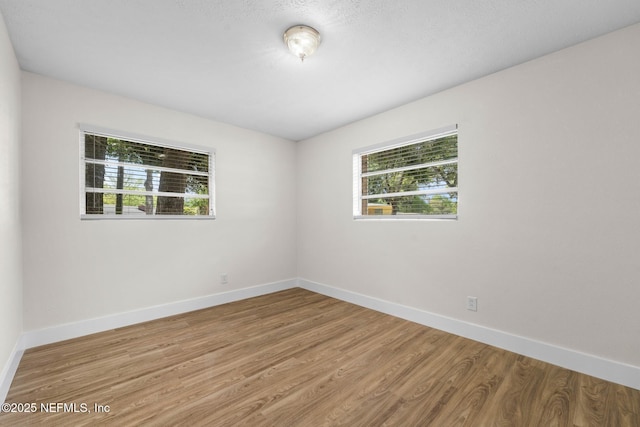 spare room with baseboards and wood finished floors