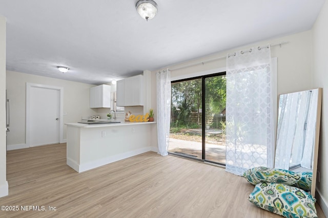 kitchen featuring light wood-style floors, light countertops, baseboards, and a peninsula