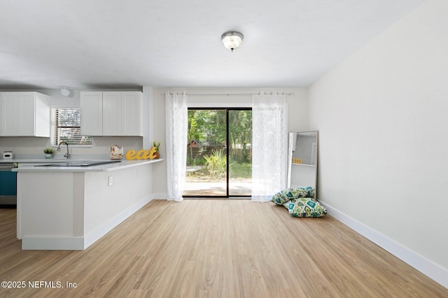 kitchen featuring light countertops, white cabinetry, baseboards, and light wood finished floors