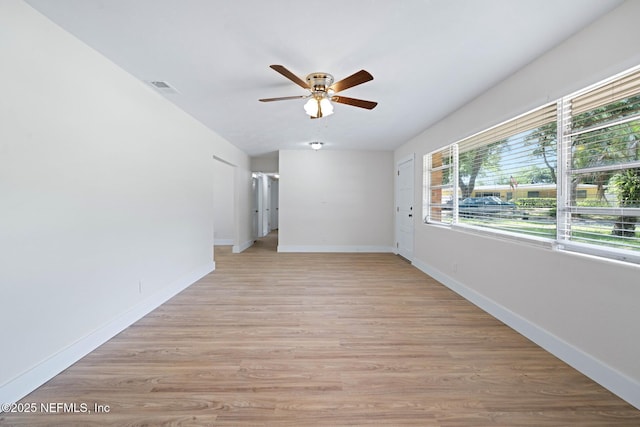 empty room with visible vents, a ceiling fan, baseboards, and light wood-style flooring