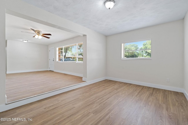 empty room featuring light wood-style floors, baseboards, and ceiling fan