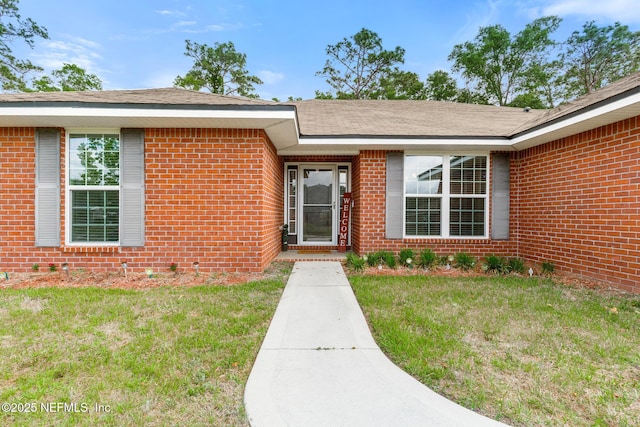entrance to property with a yard and brick siding