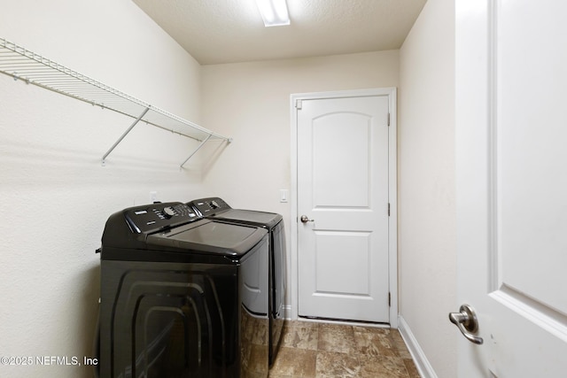 laundry area with baseboards, laundry area, stone finish flooring, and washing machine and clothes dryer