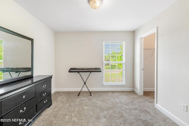 unfurnished bedroom with baseboards, carpet, and a walk in closet