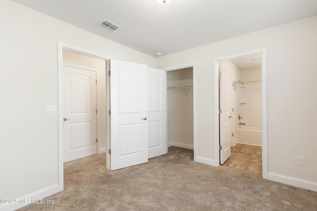 unfurnished bedroom featuring baseboards, visible vents, light carpet, and a closet