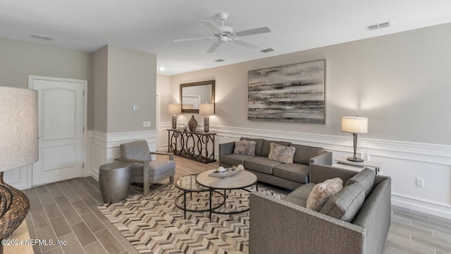 living room with visible vents, a ceiling fan, wainscoting, and wood finish floors