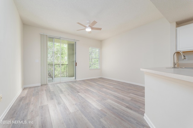 2005 Mariposa Vista Ln Unit 3-123, Saint Augustine, FL 32084 - unfurnished living room featuring baseboards, ceiling fan, a textured ceiling, a sink, and light wood-style flooring