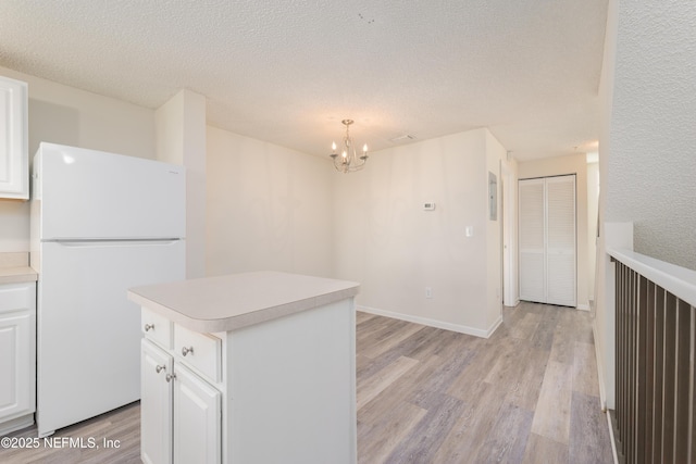 2005 Mariposa Vista Ln Unit 3-123, Saint Augustine, FL 32084 - kitchen with an inviting chandelier, light countertops, freestanding refrigerator, light wood-style floors, and white cabinetry