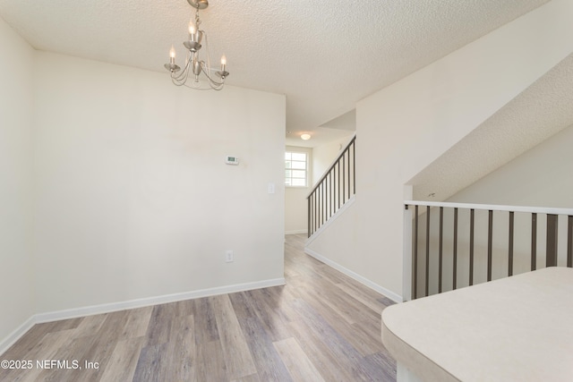 2005 Mariposa Vista Ln Unit 3-123, Saint Augustine, FL 32084 - unfurnished dining area with baseboards, a textured ceiling, wood finished floors, and a chandelier