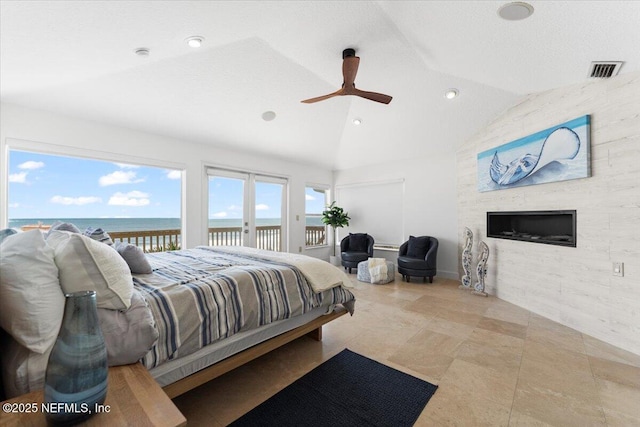 bedroom featuring visible vents, a fireplace, access to outside, a water view, and vaulted ceiling