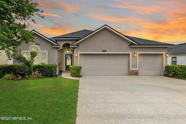 view of front facade with a garage, stucco siding, driveway, and a front yard