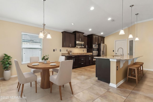 kitchen featuring dark brown cabinets, appliances with stainless steel finishes, a sink, vaulted ceiling, and ornamental molding