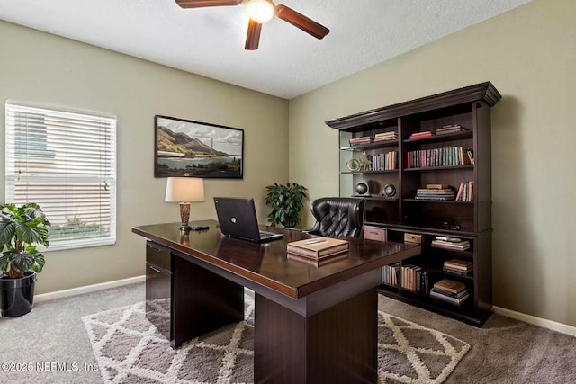 carpeted office space with baseboards and a ceiling fan