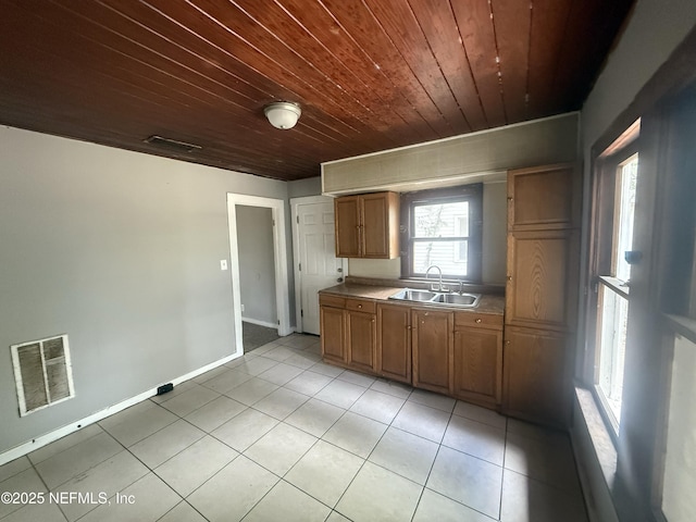 kitchen with wood ceiling, brown cabinetry, visible vents, a sink, and light tile patterned flooring