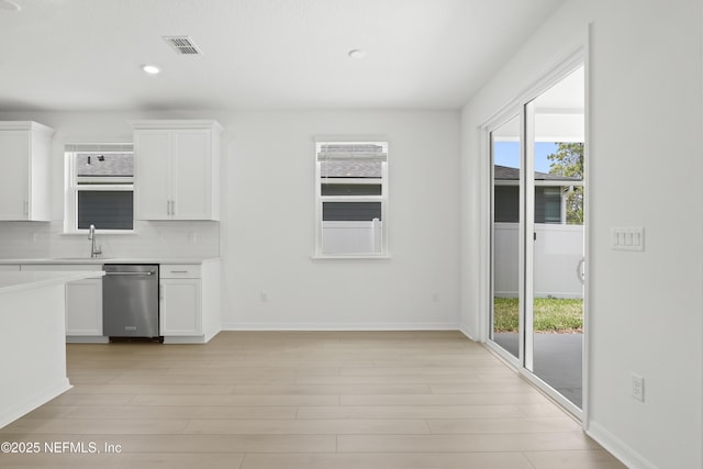 2416 Glade Ln, Green Cove Springs, FL 32043 - kitchen with stainless steel dishwasher, a sink, light countertops, white cabinets, and tasteful backsplash