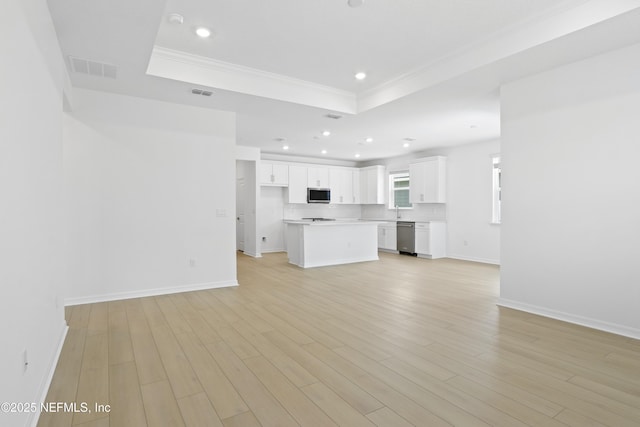 2416 Glade Ln, Green Cove Springs, FL 32043 - unfurnished living room featuring a tray ceiling, ornamental molding, baseboards, light wood finished floors, and recessed lighting