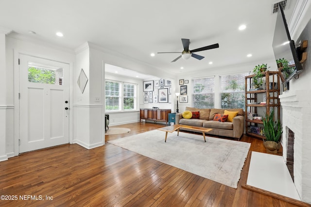 living room with a ceiling fan, visible vents, ornamental molding, and hardwood / wood-style floors
