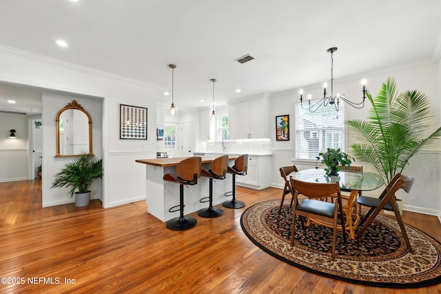 dining area with crown molding, a chandelier, light wood-style flooring, recessed lighting, and visible vents