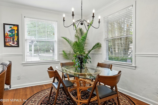 dining room featuring baseboards, ornamental molding, wood finished floors, and a chandelier