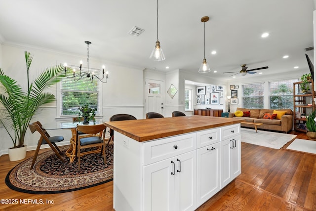 kitchen featuring crown molding, visible vents, butcher block counters, and hardwood / wood-style flooring