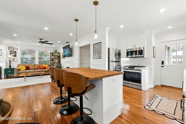 kitchen with white cabinetry, appliances with stainless steel finishes, a healthy amount of sunlight, and wooden counters