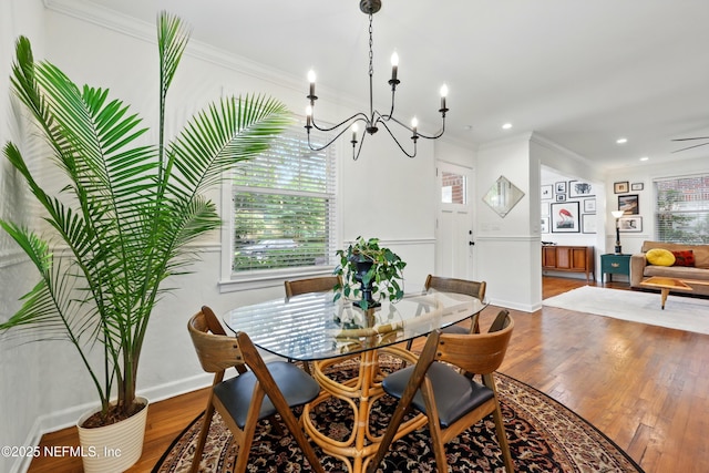 dining room featuring crown molding, a notable chandelier, a healthy amount of sunlight, and wood finished floors