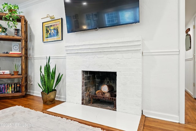 interior details featuring crown molding, baseboards, a fireplace, and wood finished floors