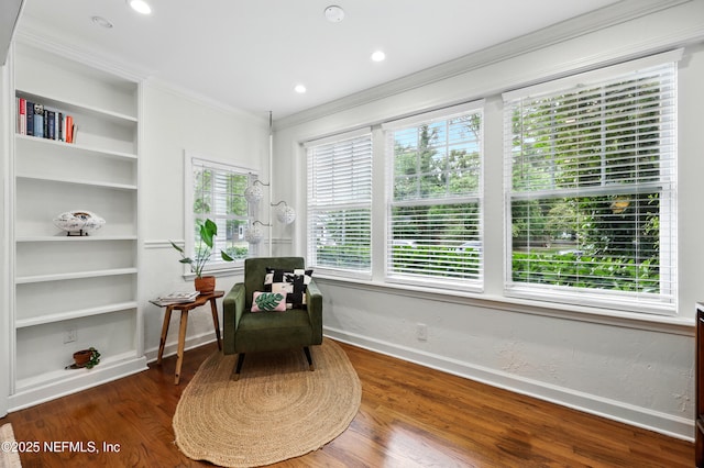 living area featuring built in features, baseboards, ornamental molding, and wood finished floors