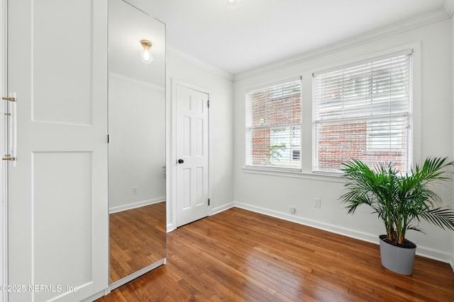 unfurnished bedroom with baseboards, ornamental molding, and wood finished floors