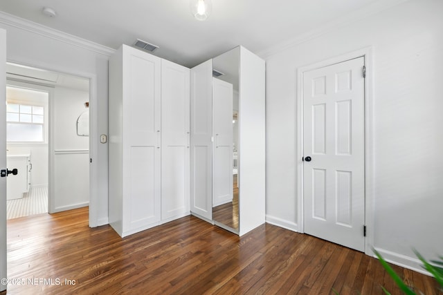 unfurnished bedroom with visible vents, crown molding, a closet, baseboards, and dark wood finished floors
