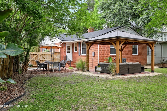 rear view of house with fence, brick siding, an outdoor hangout area, entry steps, and a yard