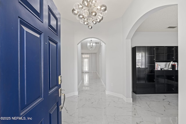 132 Summerhill Cir, Saint Augustine, FL 32086 - foyer entrance featuring arched walkways, a chandelier, and marble tiled flooring