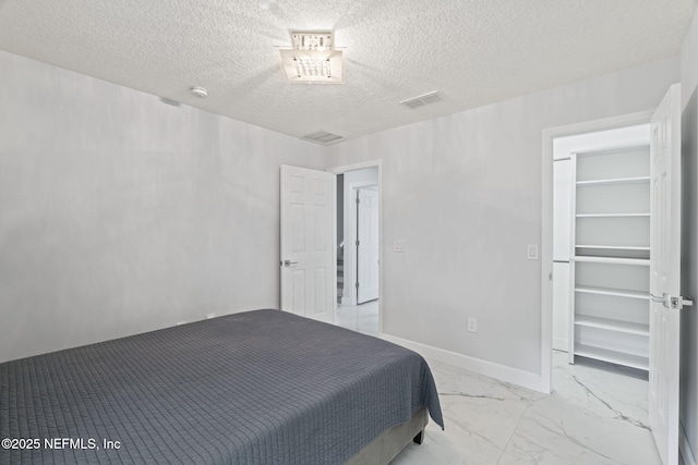 132 Summerhill Cir, Saint Augustine, FL 32086 - bedroom featuring a walk in closet, a textured ceiling, and light marble finish flooring
