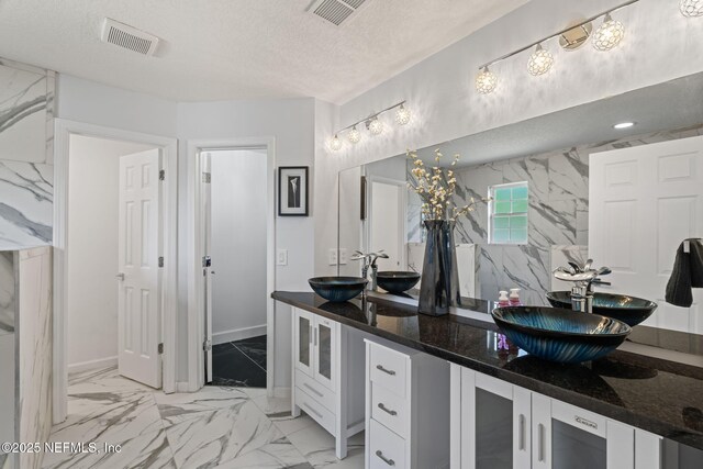 132 Summerhill Cir, Saint Augustine, FL 32086 - bathroom featuring marble look tile flooring, double vanity, and a textured ceiling