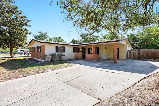 ranch-style house with fence, concrete driveway, and brick siding