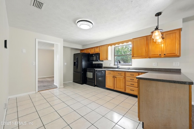 kitchen featuring visible vents, a peninsula, dark countertops, a sink, and black appliances