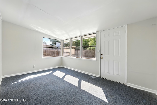 empty room with baseboards and dark colored carpet