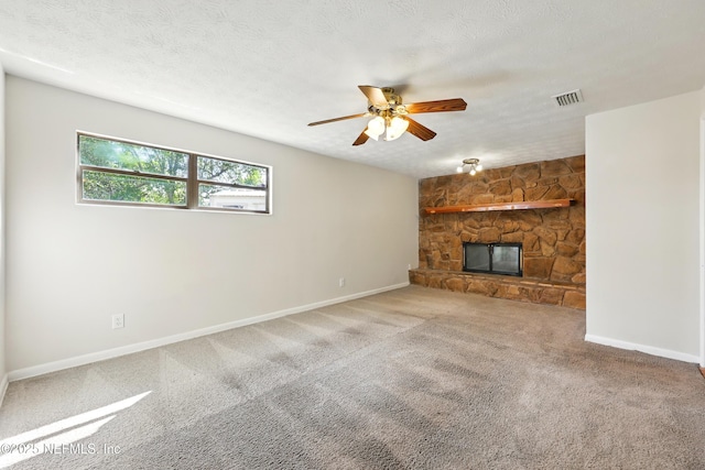unfurnished living room with a ceiling fan, a stone fireplace, visible vents, baseboards, and carpet flooring