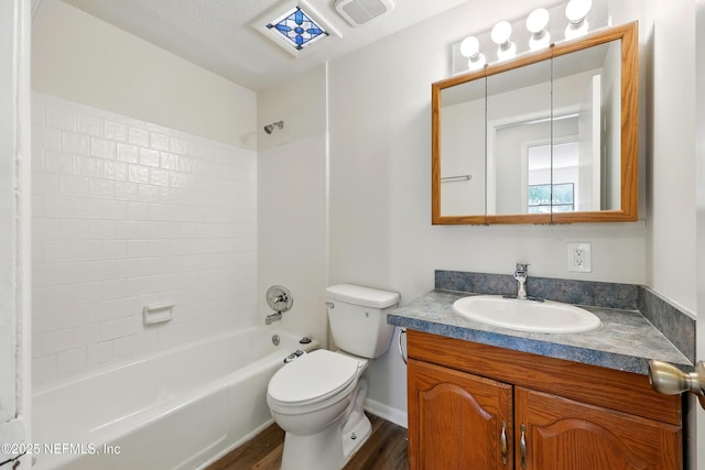 bathroom featuring vanity, toilet, wood finished floors, shower / bathing tub combination, and visible vents