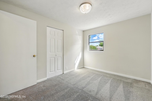 unfurnished bedroom featuring baseboards, a textured ceiling, carpet, and a closet