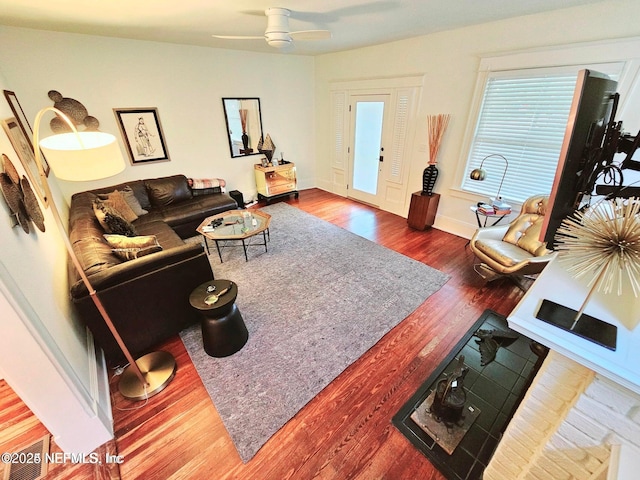 living room with baseboards, ceiling fan, and wood finished floors