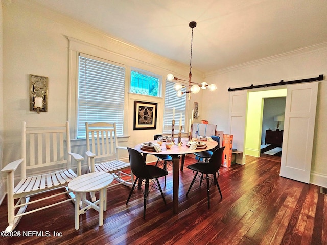 dining room featuring a barn door, ornamental molding, hardwood / wood-style flooring, and plenty of natural light