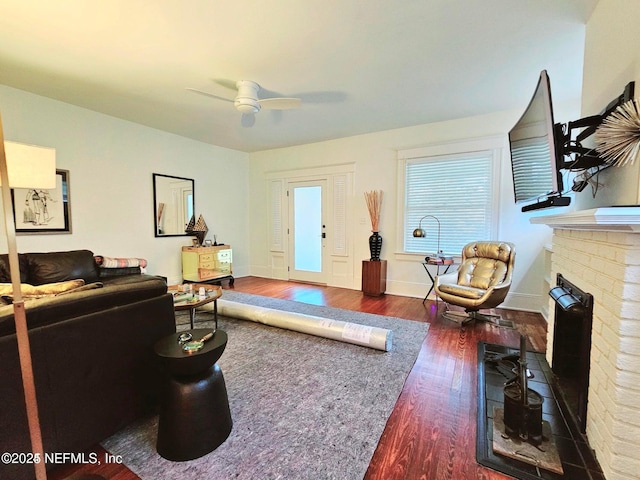 living area with baseboards, a fireplace, a ceiling fan, and wood finished floors