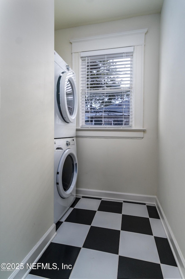washroom featuring laundry area, stacked washer and clothes dryer, baseboards, and tile patterned floors
