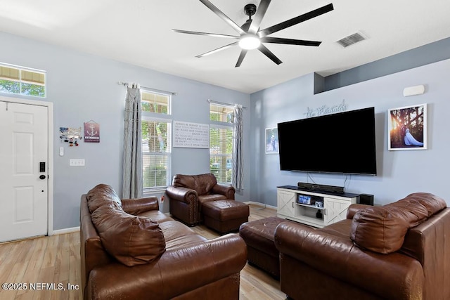 living room with ceiling fan, visible vents, baseboards, and light wood finished floors