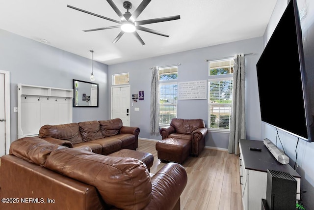 living area featuring baseboards, ceiling fan, and light wood finished floors