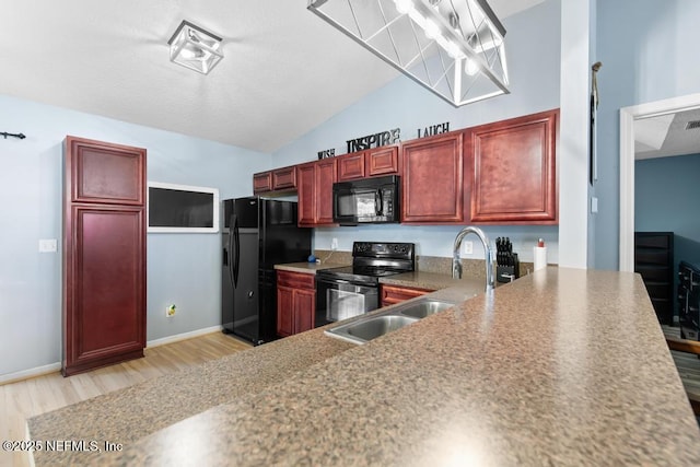 kitchen featuring light wood-style floors, vaulted ceiling, black appliances, and reddish brown cabinets