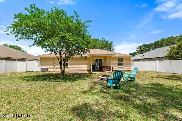 back of property with a yard, a fenced backyard, and an outdoor fire pit