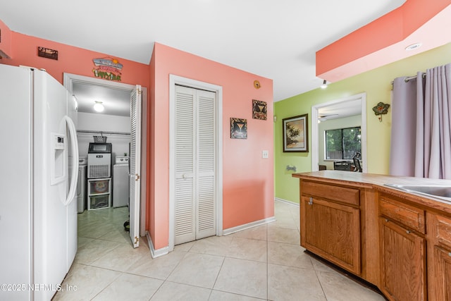 4030 Tyndel Creek Pl, Jacksonville, FL 32223 - kitchen with white fridge with ice dispenser, washer / dryer, light tile patterned flooring, and brown cabinets